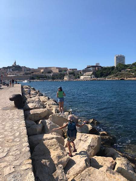 Das Bild zeigt meine Kinder, wie sie auf den Felsen am Hafen von Marseille klettern.
