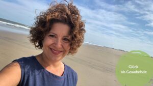 Pia Hübinger am Strand, lächelnd — Glück als Gewohnheit