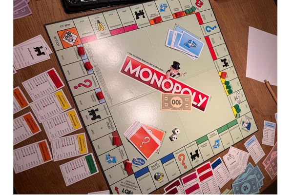 Das Bild zeigt ein Monopoly-Spielbrett mit den dazugehörenden Spielkarten.